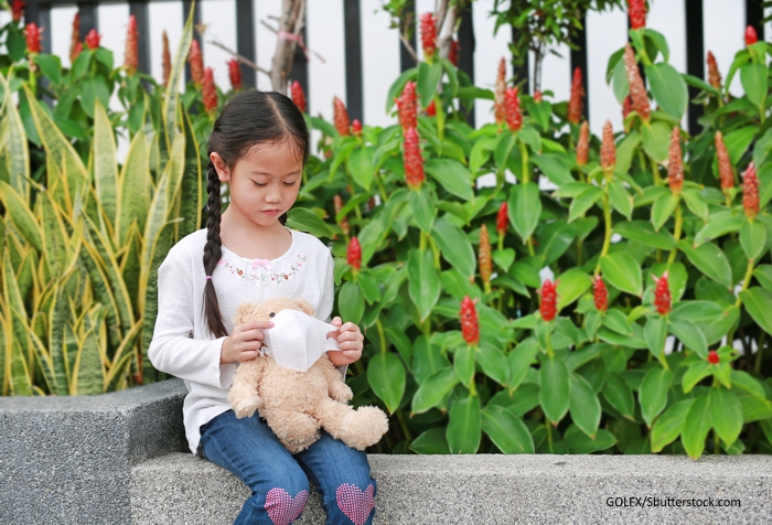 child putting mask on teddy bear